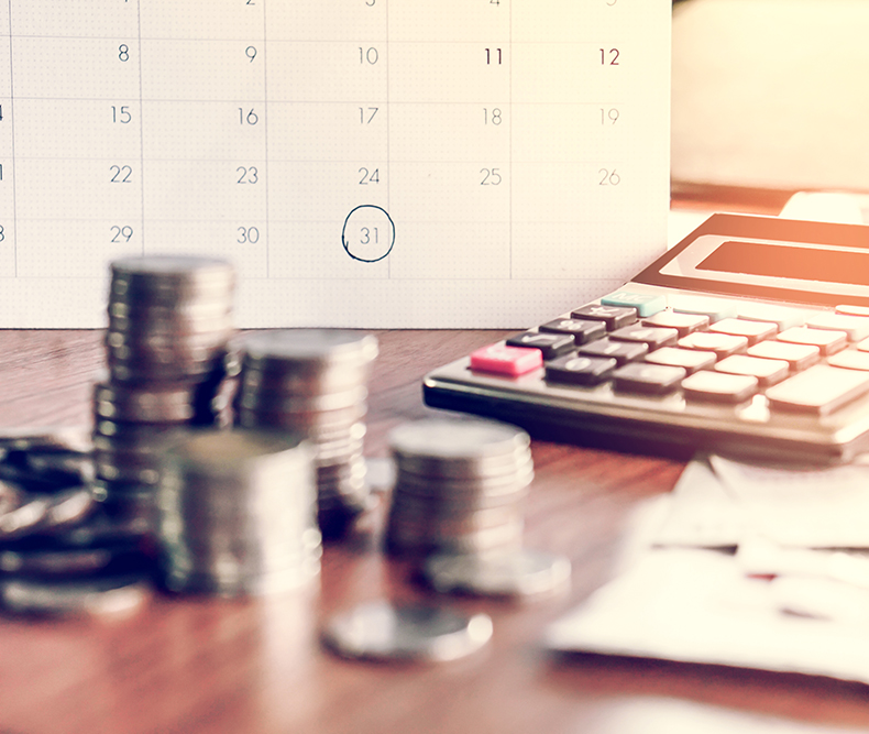 Calendario, calculadora y monedas sobre un escritorio